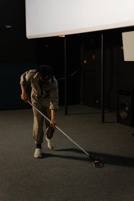 A professional cleaning specialist from Carpet Cleaners W1W dressed in a full white protective suit, face mask, and orange gloves, operating a portable vacuum cleaner in a modern, well-lit residential